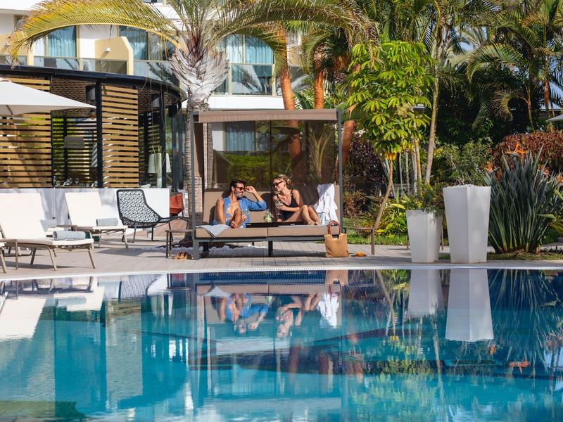 Ontspannen mensen bij het zwembad in een tropische hotel tuin.