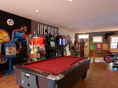 Interno di una sala giochi con tavolo da biliardo, slot machine e giochi arcade in un hotel.