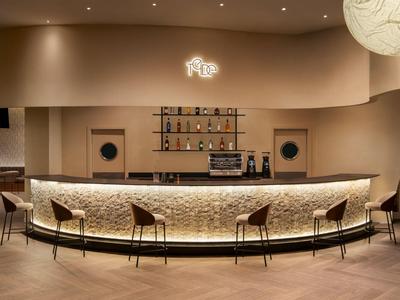 Bar elegante in hotel con bancone in pietra illuminato e sgabelli in ambiente moderno