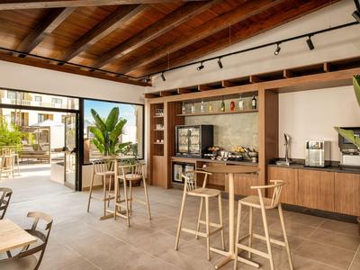 Sala colazioni moderna e luminosa con mobili in legno e piante, con accesso a una terrazza.