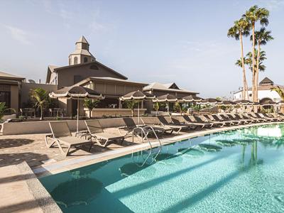 Piscina dell'hotel con lettini e ombrelloni sotto un cielo azzurro