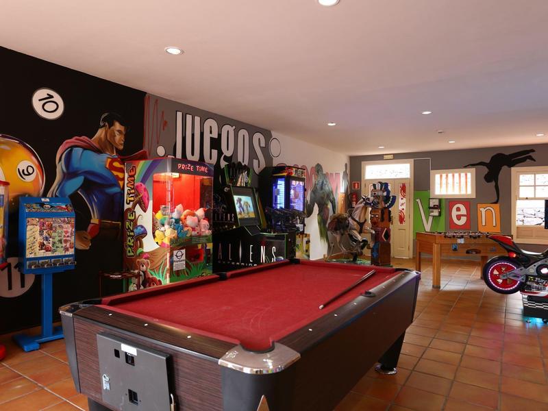 Pokój gier z stołem do bilarda, automatami do gier i miejscem do siedzenia w jasnym pomieszczeniu.