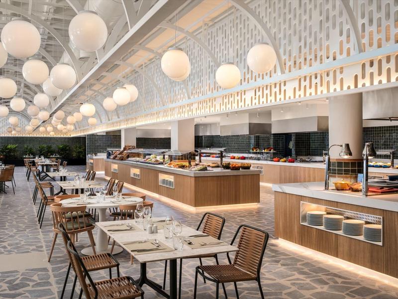 Nowoczesna restauracja z nakrytymi stołami i wiszącymi kulistymi lampami.