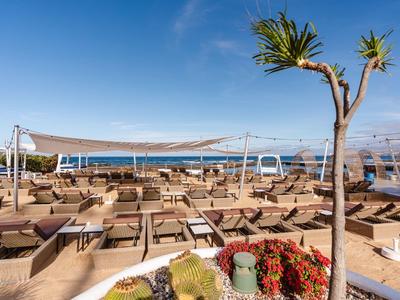 Hotel przy plaży z wieloma leżakami i krzesłami pod błękitnym niebem nad morzem