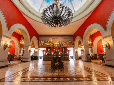 Luksusowa hol hotelowy z czerwonymi ścianami, wysokimi łukami i dużym żyrandolem