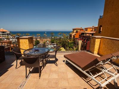 Terrace with table, chairs, and sun loungers overlooking the sea under a clear sky