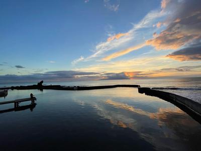 Wieczorny widok na spokojne jezioro z chmurami i odbiciem w wodzie.