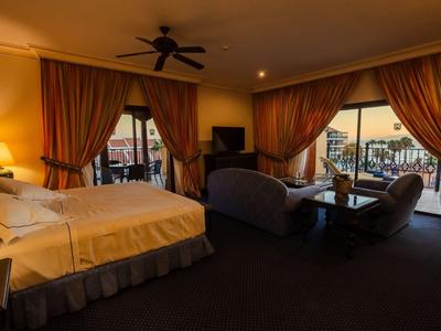 Cozy hotel room with large bed, seating area, and balcony view at dusk.