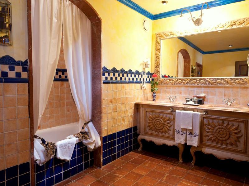 Elegancka łazienka z pozłacanym lustrem, niebiesko-białymi kafelkami i drewnianymi meblami.