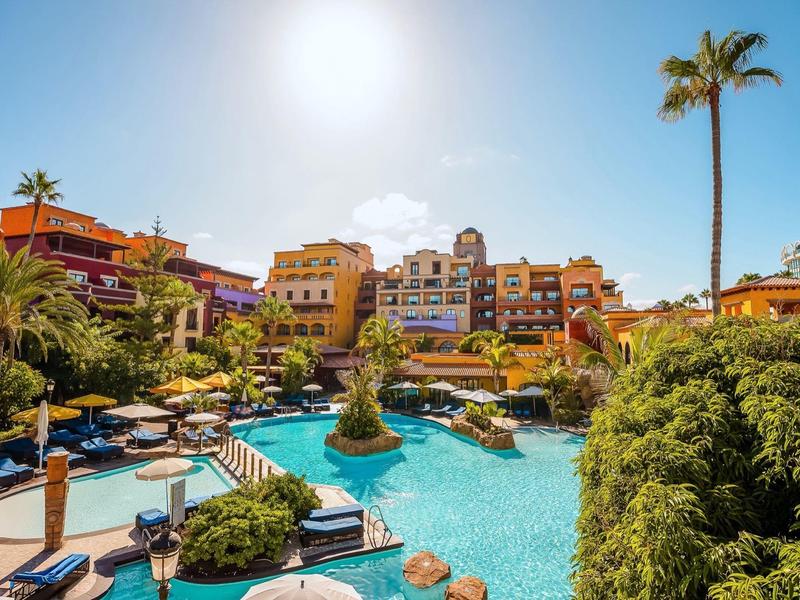 Basen hotelowy z palmami i leżakami pod słonecznym, niebieskim niebem