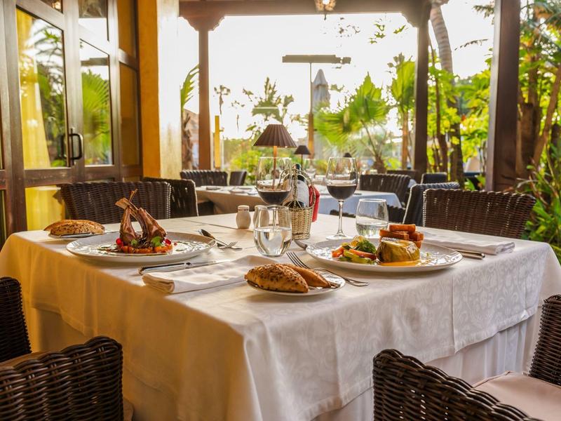 Elegancko nakryty stół na słonecznym tarasie z widokiem na zieleń.