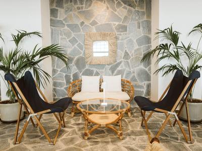 Accogliente zona salotto con sedie nere, tavolo rotondo e parete in pietra in hotel.