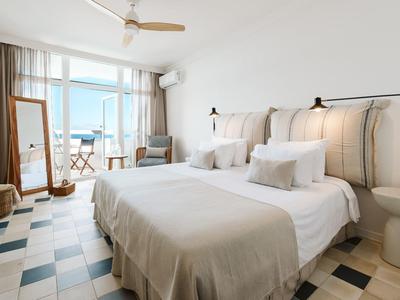 Camera d'hotel luminosa con letto matrimoniale, grande finestra e balcone con vista mare.