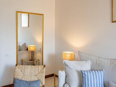 Soggiorno luminoso con divano, poltrona, lampada da terra e grande specchio rettangolare da parete