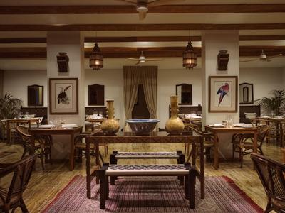 Accogliente area ristorante in hotel con mobili in legno, tappeti e quadri di uccelli.