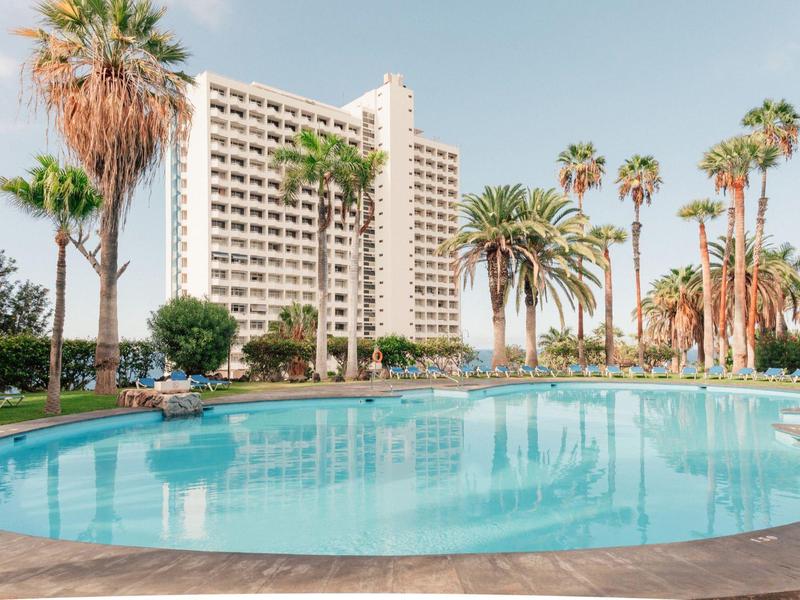 Hotel con grande piscina e palme sotto un cielo limpido