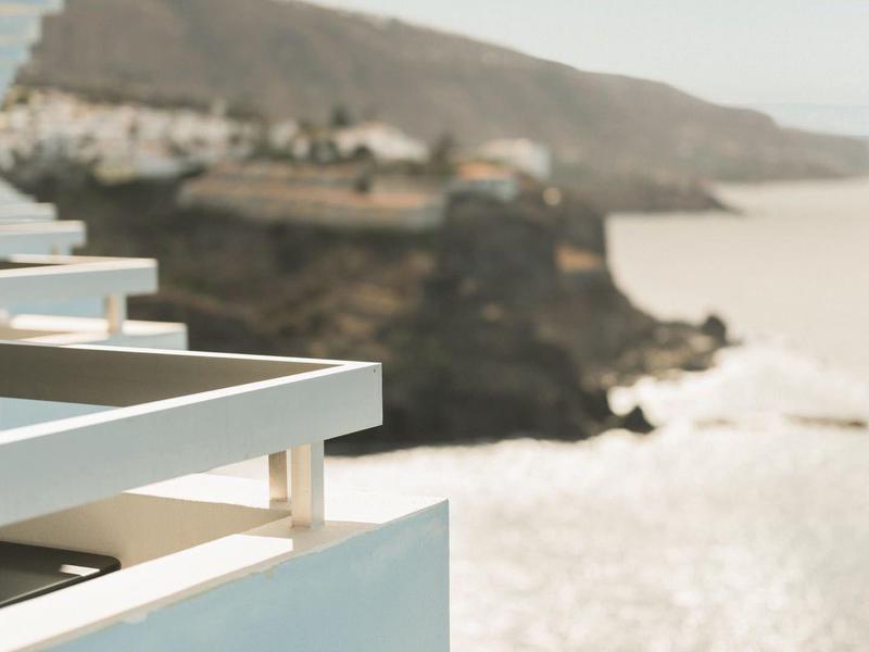 Vista da un balcone moderno sulla costa rocciosa e mare calmo sotto un cielo sereno.