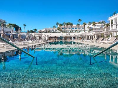 Piscina azzurra limpida con lettini e palme in un resort soleggiato.