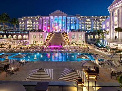 Groot hotel met verlicht zwembad en versierde entree 's nachts