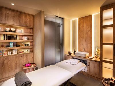 Accogliente stanza spa con lettino da massaggio, scaffali in legno e luce soffusa.