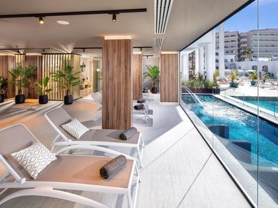 Salotto interno moderno con sedie reclinabili con vista su piscina esterna e città.