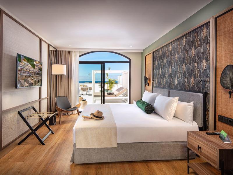 Camera d'hotel moderna con letto grande, balcone, pavimento in legno e arredamento contemporaneo.