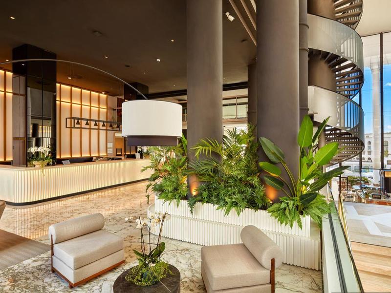 Lussuosa hall dell'hotel con design moderno, comode sedute, piante e grandi finestre con vista sulla città.