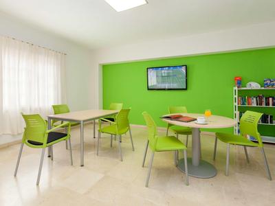 Světlá společenská místnost se zelenou zdí a moderním nábytkem.