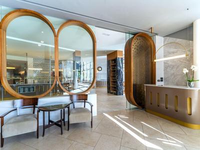 Heller Hotellobby mit runden Holzakzenten, Sitzbereich und Empfangstheke bei Tageslicht.