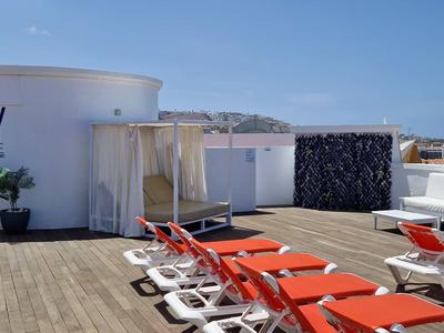 Dachterrasse mit roten Liegestühlen, weißer Lounge und blauer Himmel