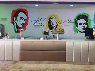 Thekenbereich mit vier farbigen Pop-Art-Porträts an der Wand in einem Hotel oder Cafe.