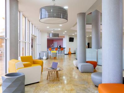 Helles, modernes Wohnzimmer mit großen Fenstern, bunter Sitzmöbel und Holzfußboden.