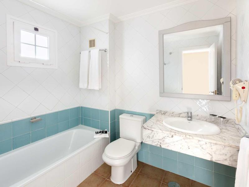 Helles Badezimmer mit weißer Badewanne, weißer Toilette und Marmor-Waschbeckenplatte.