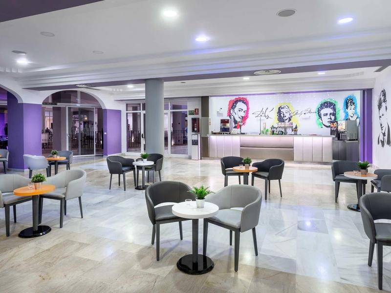 Moderner Caféraum mit Tischen, Stühlen und bunten Wandbildern in hellem, offenem Raum.