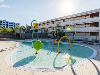 Piscina per bambini con giochi d'acqua colorati in un cortile soleggiato dell'hotel.