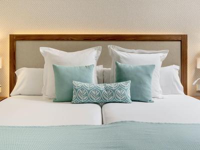 Starannie pościelone łóżko podwójne z białymi i niebieskimi poduszkami w pokoju hotelowym.