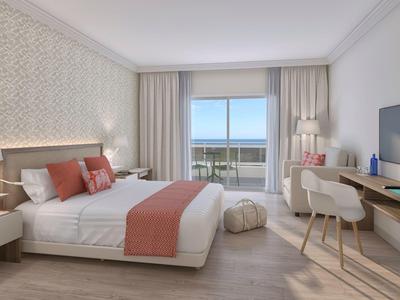 Camera luminosa con letto matrimoniale, vista mare e arredamento moderno.