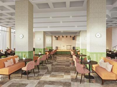 Ruime hotel lounge met gestoffeerde stoelen en sofa's, grote ramen en heldere plafond.