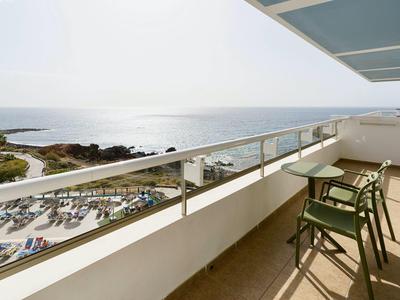 Balcone luminoso con sedie e vista sul mare calmo e sulla spiaggia.