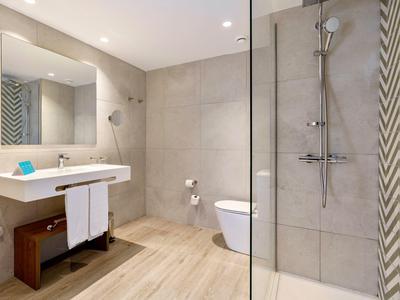 Bagno moderno con doccia, lavabo, WC e piastrelle beige.