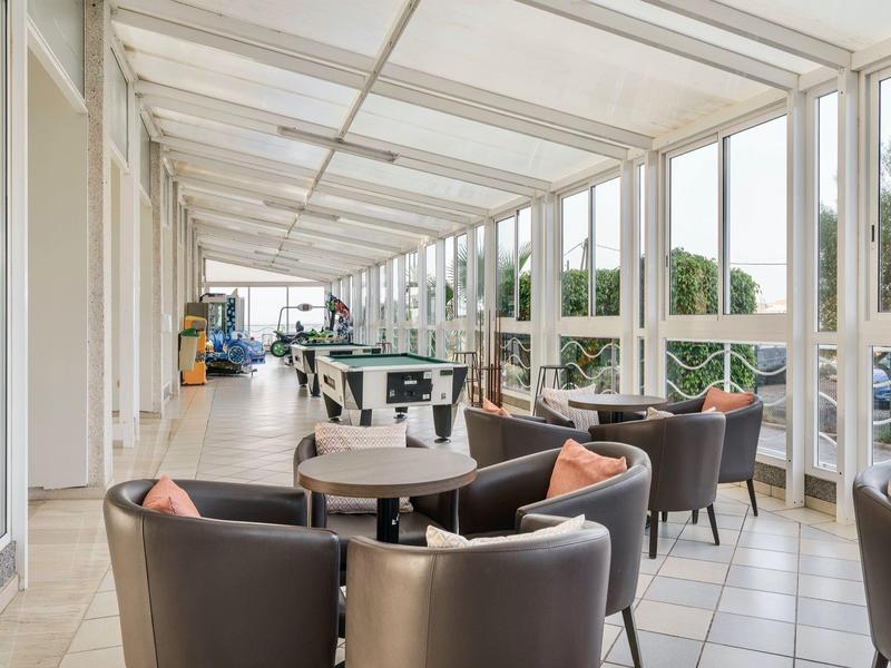 Terrazza coperta con sedie comode e tavoli rotondi, vista sulla natura.