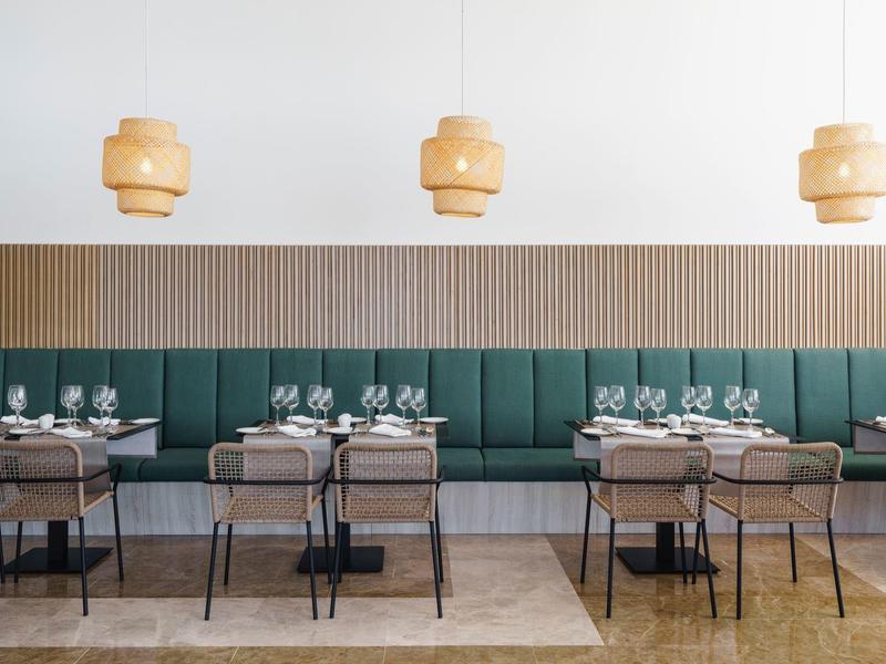 Interno di ristorante moderno con divanetti verdi e lampade a sospensione in legno.