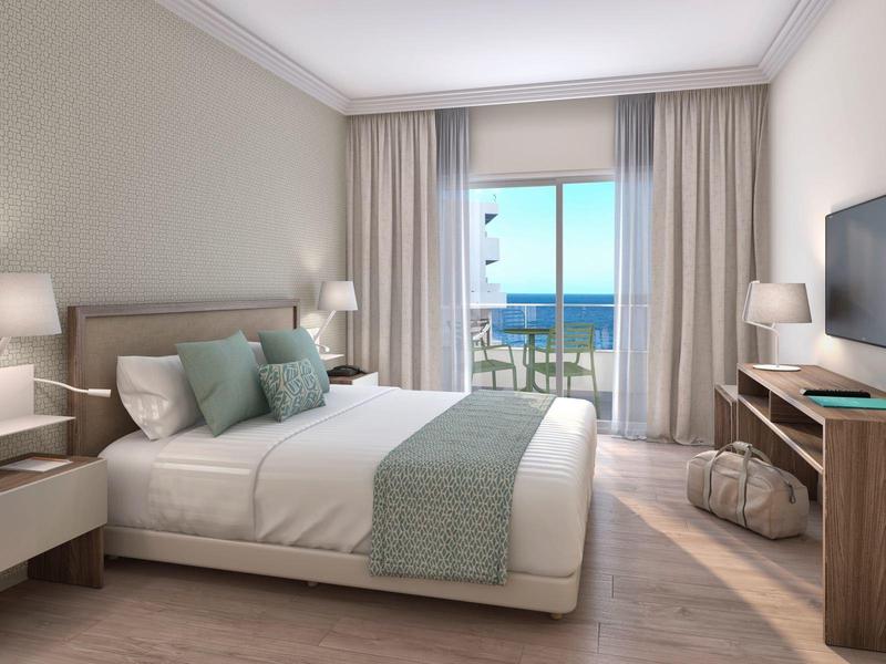 Camera d'hotel elegante con letto king-size e vista sul mare dal balcone.
