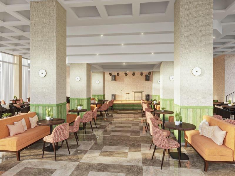 Sala ristorante di un hotel con divani arancioni e sedie rosa.