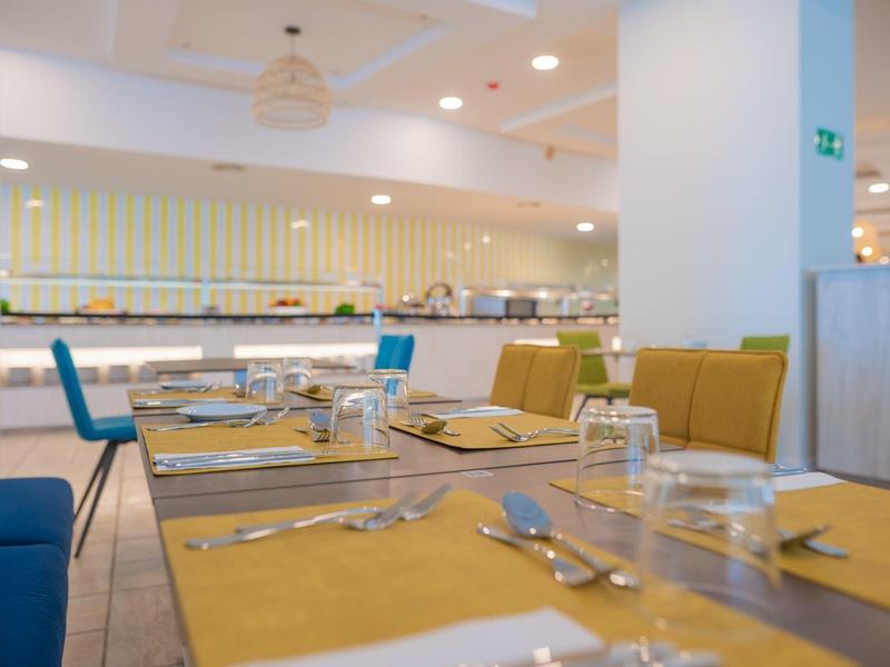 Sala da pranzo moderna con tavoli apparecchiati e sedie colorate in un hotel.