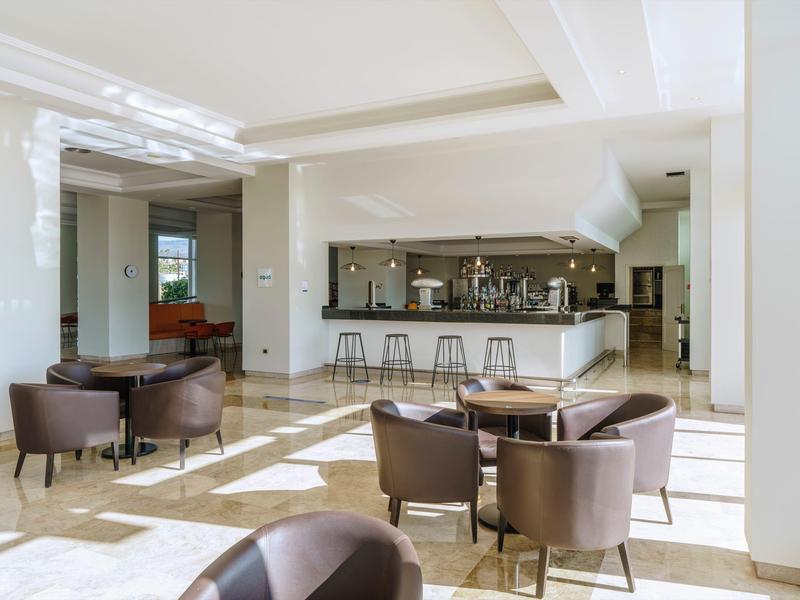 Lounge luminoso con poltrone marroni e bar moderno in uno spazio ampio.