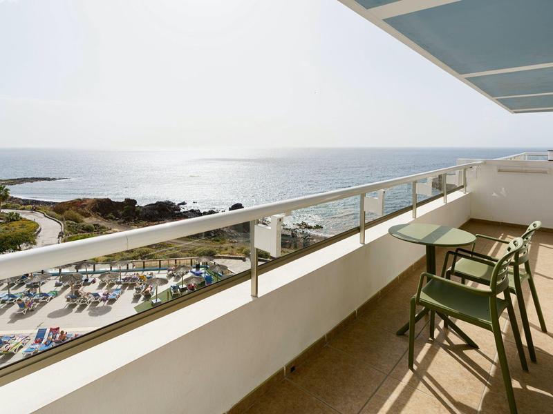 Balcone luminoso con sedie e vista sul mare calmo e sulla spiaggia.