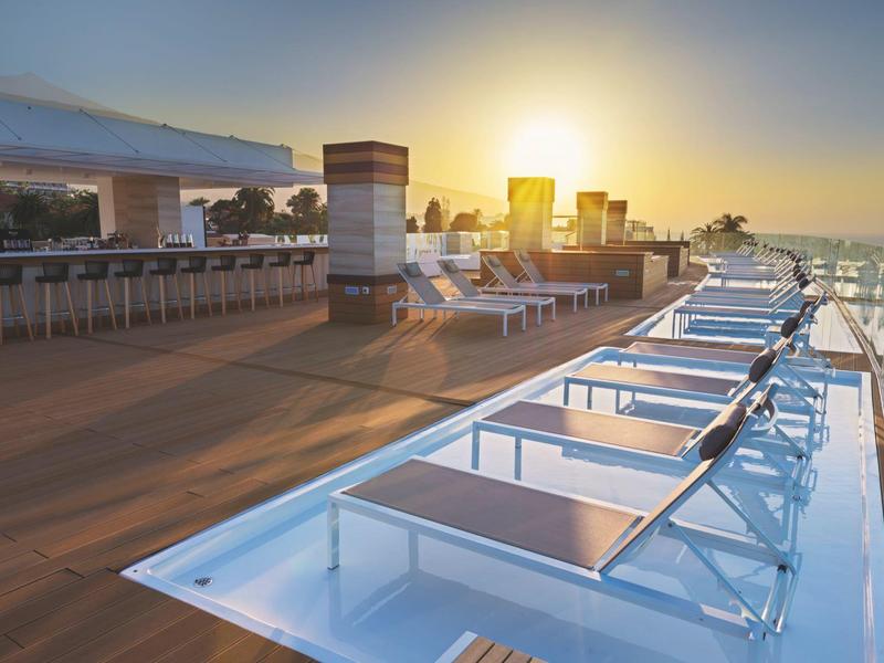 Terrasse sur le toit avec chaises longues et coucher de soleil sur la mer