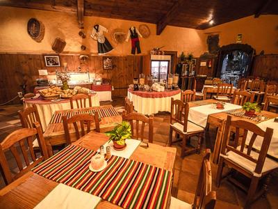 Ristorante rustico con mobili in legno, tovaglie decorate e luce calda.