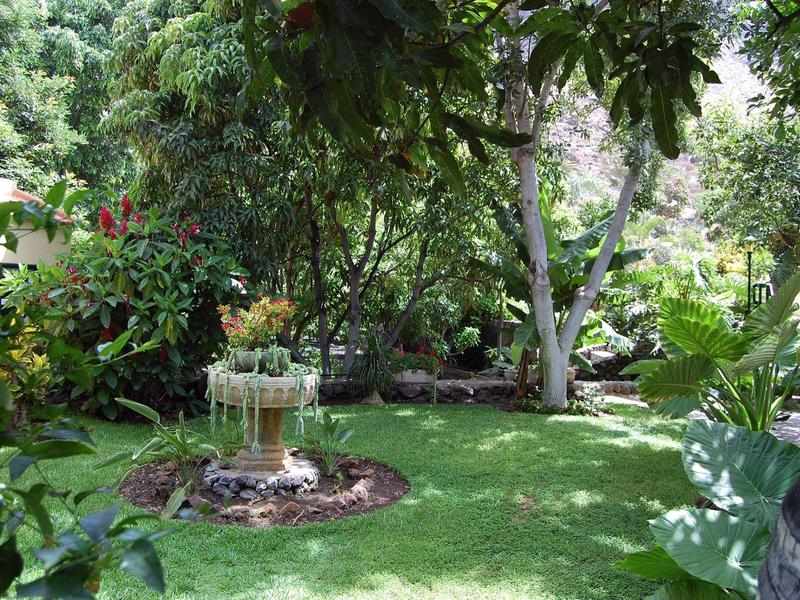 Grüner Garten mit Bäumen, Rasen und einem kleinen Blumenbeet in einem Hotelgarten.